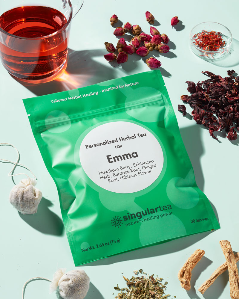 Personalized herbal tea pack next to a glass of tea and herbs
