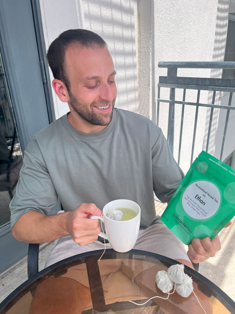 Customer holding a personalized SingularTea pouch and a cup of tea