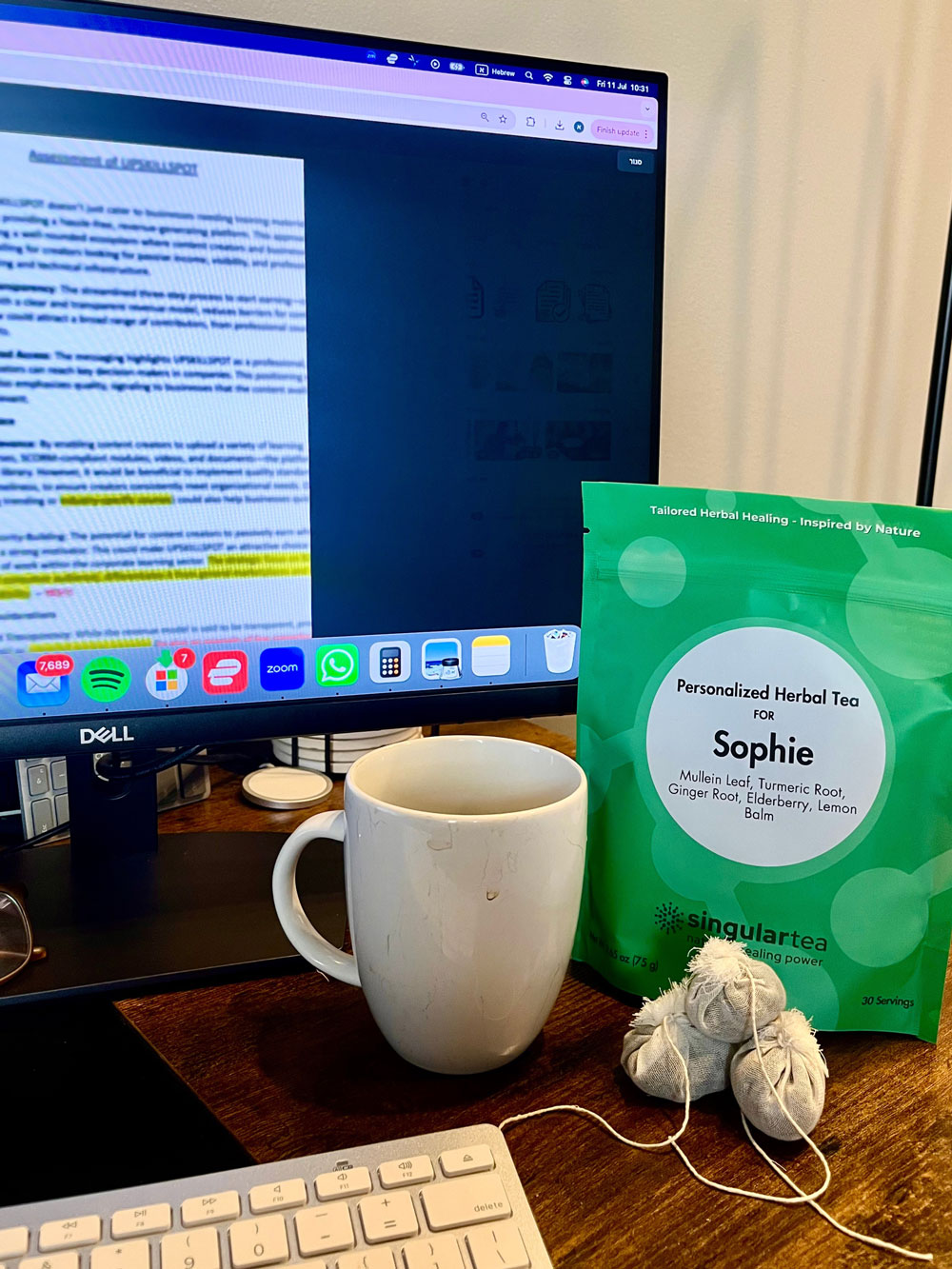Desk with mug; SingularTea personalized remedy pouch labeled ‘Sophie’ and two premium cotton tea bags.